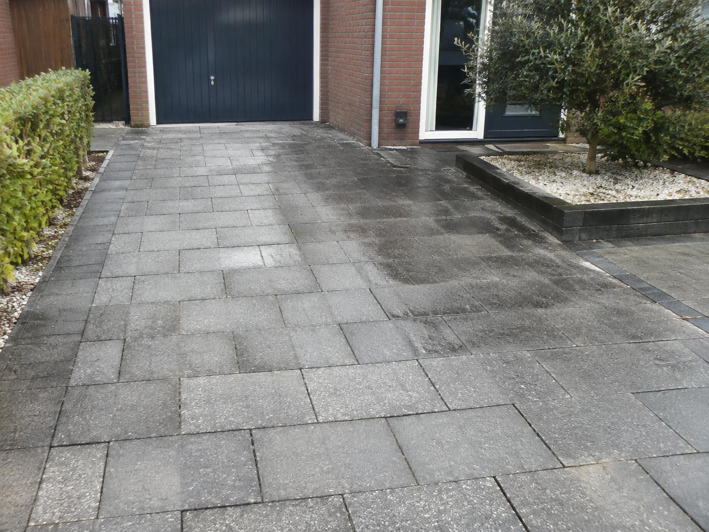 Grijze bestrating van een oprit die deels is gereinigd
